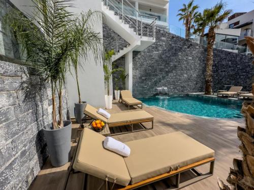 a patio with lounge chairs and a swimming pool at Beach Walk Luxury Suites in Agios Nikolaos