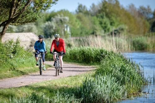 dwoje ludzi jeżdżących rowerami na ścieżce obok rzeki w obiekcie Honeybee Cottage 15P w mieście North Petherton