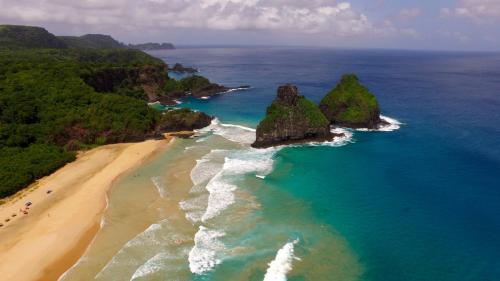 uma vista aérea de uma praia com rochas no oceano em Pousada Flôr do Atlântico em Fernando de Noronha