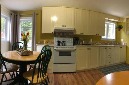 une cuisine avec des armoires jaunes, une table et une cuisinière dans l'établissement Séjour, Flèche du fjord, vue Saguenay, Mont Valin, à Saint-Fulgence