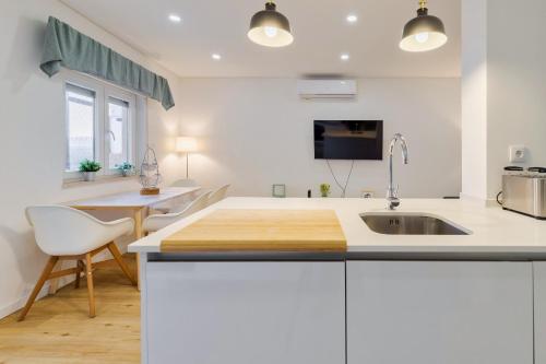 a white kitchen with a sink and a table at Fonte Nova Nest in Setúbal