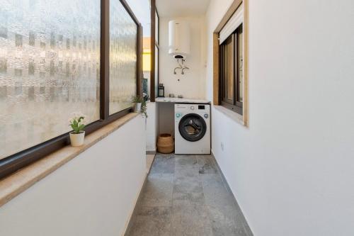a laundry room with a washing machine and windows at Fonte Nova Nest in Setúbal
