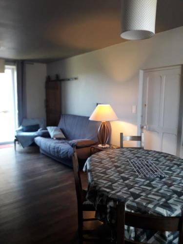 un salon avec une table et un canapé bleu dans l'établissement Maison de Vacances, à Châteaumur