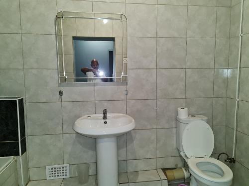 a bathroom with a sink and a toilet and a mirror at Hasate Guest House 10 Florence street Oakdale Belliville 7530 cape town south African in Cape Town