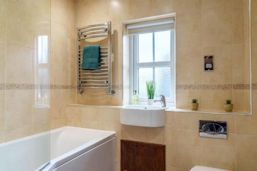 a bathroom with a tub and a sink and a window at Nannycroft Cottage in Beckermet