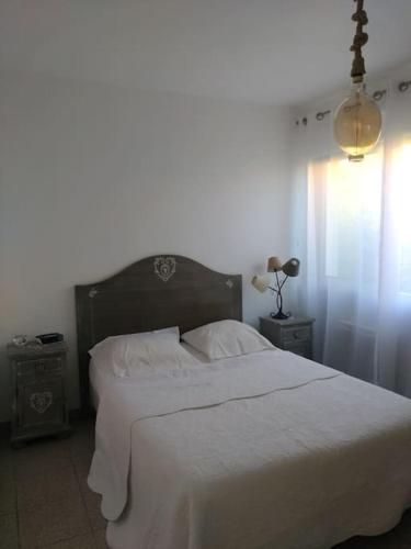 une chambre avec un grand lit avec des draps blancs dans l'établissement Maison proche de la mer, au Barcarès