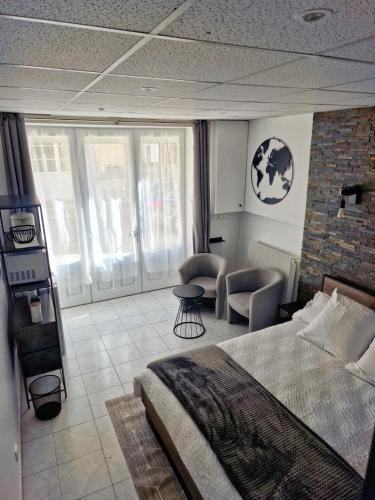 a bedroom with a bed and a chair and windows at Au bonheur des ruelles in Monpazier