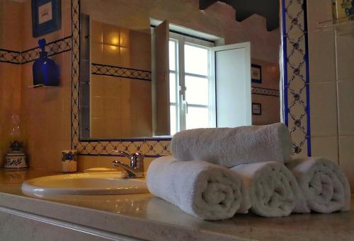Baño con toallas en un lavabo con espejo en Castelo de Bode Monte do Valinho Country house with private pool and panoramic views, en Alverangel