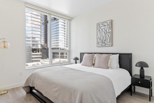 a white bedroom with a large bed and two windows at Downtown 1BR w Roof Pool Gym nr the 110 LAX-734 in Los Angeles