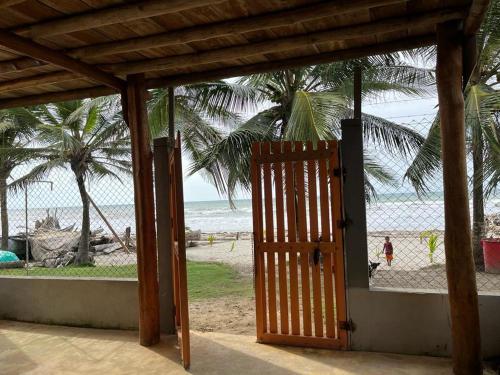 an open door to a beach with palm trees and the ocean at Cabaña El Paraíso Uveros in San Juan de Urabá