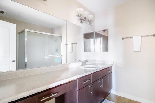 Un baño con lavabo y un espejo grande. en Foster City 2BR w Gym Pool WD nr highways SFO-567, en Foster City