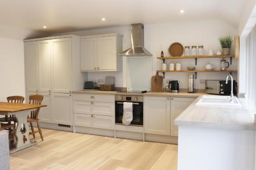 a kitchen with white cabinets and a wooden table at Cowley Farm, Preston Bissett, Buckingham in Buckingham