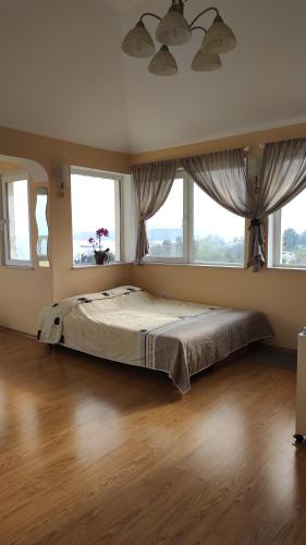 a bedroom with a large bed with windows at Trakata Villa Apartments in Varna City