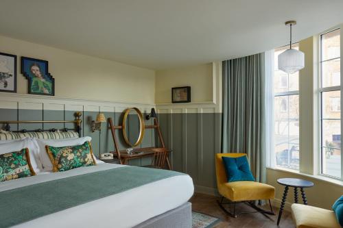 Hotel Indigo - Exeter, an IHG Hotel في إكسيتير: غرفة نوم بسرير وكرسي ومرآة