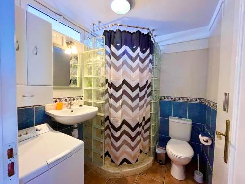 ein Badezimmer mit Waschbecken, WC und Duschvorhang in der Unterkunft Borinquen Sky Apartments in Playa de las Americas