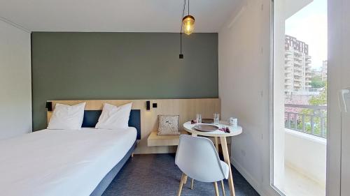 a bedroom with a bed and a table and a window at City Résidence Paris Saint-Maurice in Saint-Maurice