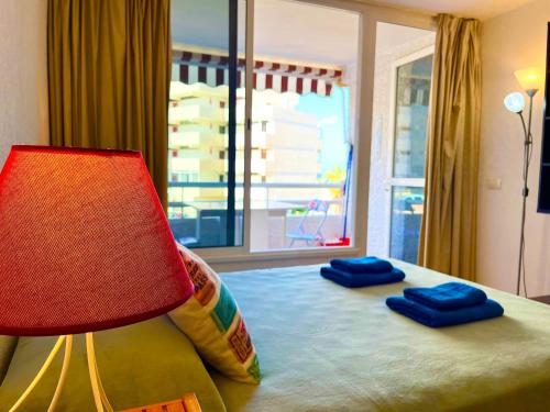 um quarto com uma cama com um candeeiro e uma janela em Borinquen Sky Apartments em Playa de las Americas