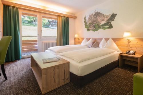 a hotel room with a large bed and a window at Hotel Restaurant Alpina in Grindelwald