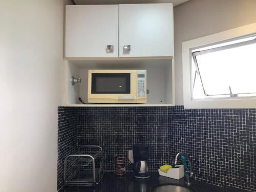 a kitchen with a microwave oven above a sink at Royal Ibirapuera Park in São Paulo