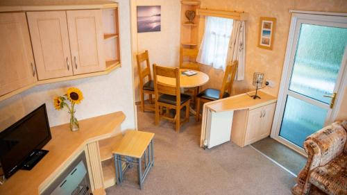 Dieses kleine Zimmer verfügt über einen Schreibtisch und einen Tisch mit einem TV. in der Unterkunft The Beeches Static Caravan in Cullompton
