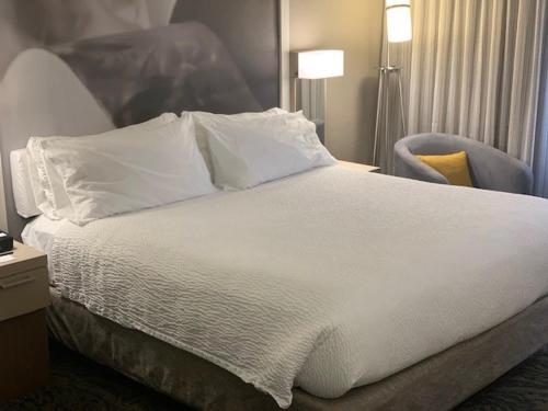 a white bed with pillows and a chair in a room at Courtyard by Marriott Hickory in Hickory