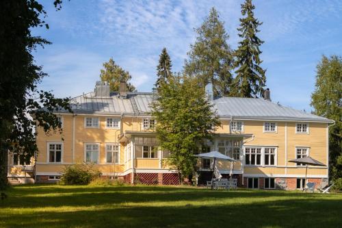 una gran casa amarilla con un gran patio en Landhaus Kekkola, en Mikkeli