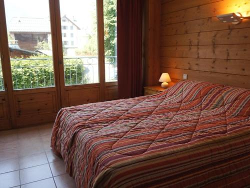 1 dormitorio con 1 cama con pared de madera en Appartement Chamonix-Mont-Blanc, 3 pièces, 4 personnes - FR-1-507-34 en Chamonix-Mont-Blanc