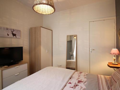 une chambre avec un lit et une télévision à écran plat dans l'établissement Charmant T2 Bis au Mont-Dore, centre-ville, WIFI, à 100m des Thermes - FR-1-608-47, à Le Mont-Dore