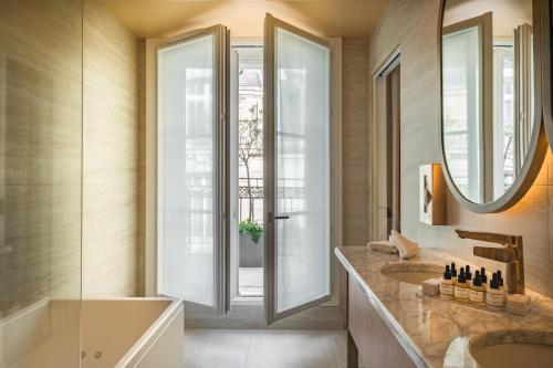 a bathroom with a tub and a sink and a mirror at Hôtel Le Monna Lisa by Inwood Hotels in Paris