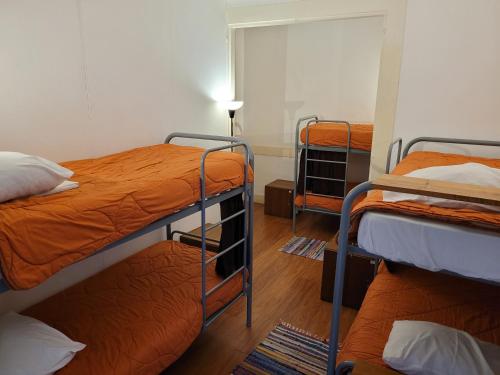 a room with three bunk beds with orange sheets at inBraga Hostel in Braga