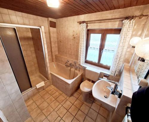 a bathroom with a tub shower and a sink and a toilet at Pension Etzerschlössl in Berchtesgaden
