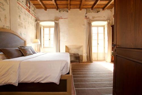 ein Schlafzimmer mit einem Bett in einem Zimmer mit Fenstern in der Unterkunft Hotel San Giovanni Resort in Saluzzo