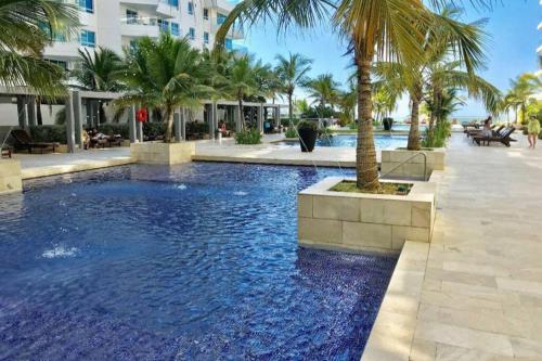 ein Pool mit Palmen und ein Gebäude in der Unterkunft LUJOSO Apartamento en Cartagena Incluye Servicio Domestico in Cartagena de Indias