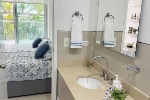 ein Bad mit einem Waschbecken und ein Bett mit einem Spiegel in der Unterkunft LUJOSO Apartamento en Cartagena Incluye Servicio Domestico in Cartagena de Indias