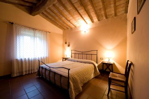 Schlafzimmer mit einem Bett und einem Fenster in der Unterkunft Antico Borgo Poggiarello in Monteriggioni