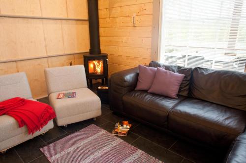 uma sala de estar com um sofá de couro e um fogão em Villa Valmuska em Mikkeli