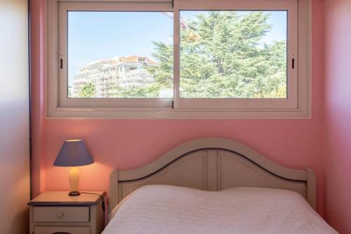 Dormitorio con ventana, cama y lámpara en A6- 3p Antibes Garoupe vue mer terrasse clim garage en Antibes