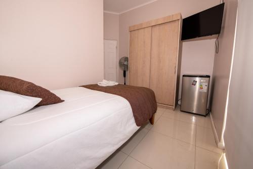 a small bedroom with a bed and a refrigerator at Hotel San Francisco De la Selva in Copiapó