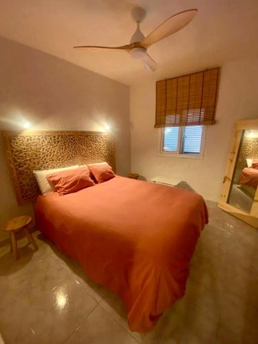 a bedroom with a large orange bed with a fan at Casita Pepe in Jávea