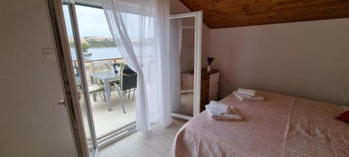 a bedroom with a bed and a balcony with a table at Apartmani S&S in Stara Novalja