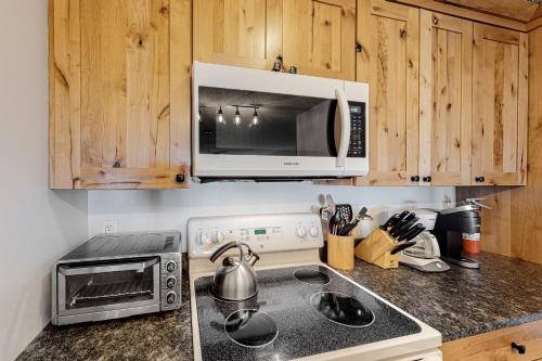a kitchen with a microwave and a stove top oven at Okemo Trailside 22DL Shred Shack in Ludlow