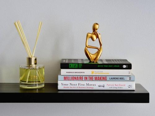 a stack of books sitting on a shelf with a statue at iNqaba @Ellipse Waterfall in Midrand