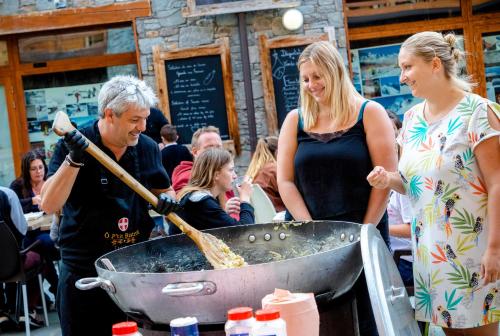 a group of people standing around a grill with pizza at Résidence Club mmv L'Étoile des Cimes **** in Sainte-Foy-Tarentaise