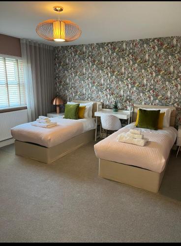 a room with two beds and a table in it at The Heyford Hotel in Upper Heyford