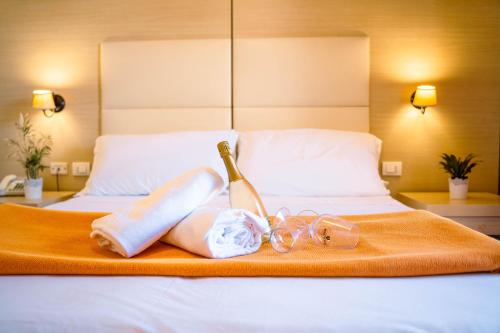 a bed with two towels and a bottle and glasses at Taormina Hotel Calipso in Mazzeo