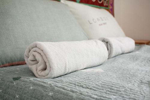 two towels are rolled up on a bed at Guest House Altyn Oimok in Bokonbayevo