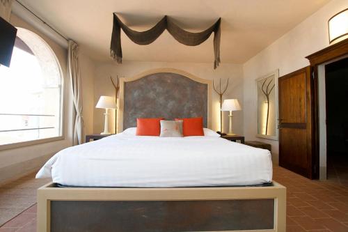 a bedroom with a large white bed with red pillows at Hotel San Giovanni Resort in Saluzzo