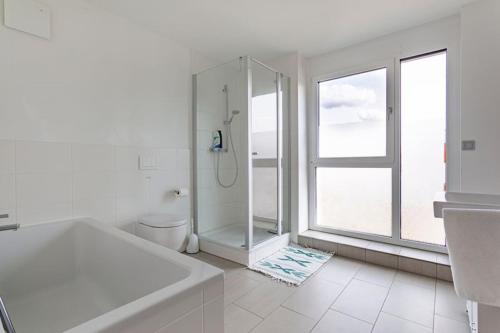 ein weißes Bad mit einer Dusche und einer Badewanne in der Unterkunft Privat Zimmer Richtung Messe in Hannover