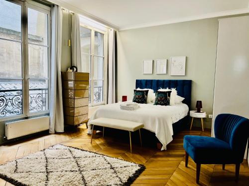 een slaapkamer met een bed en een blauwe stoel bij Luxury Flat in Le Marais - Central Paris in Parijs