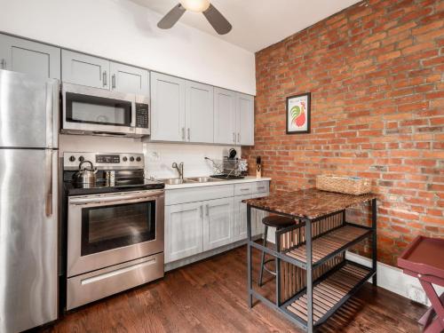 a kitchen with stainless steel appliances and a brick wall at Cute German Village Lilhauscity Parkpetsok in Columbus